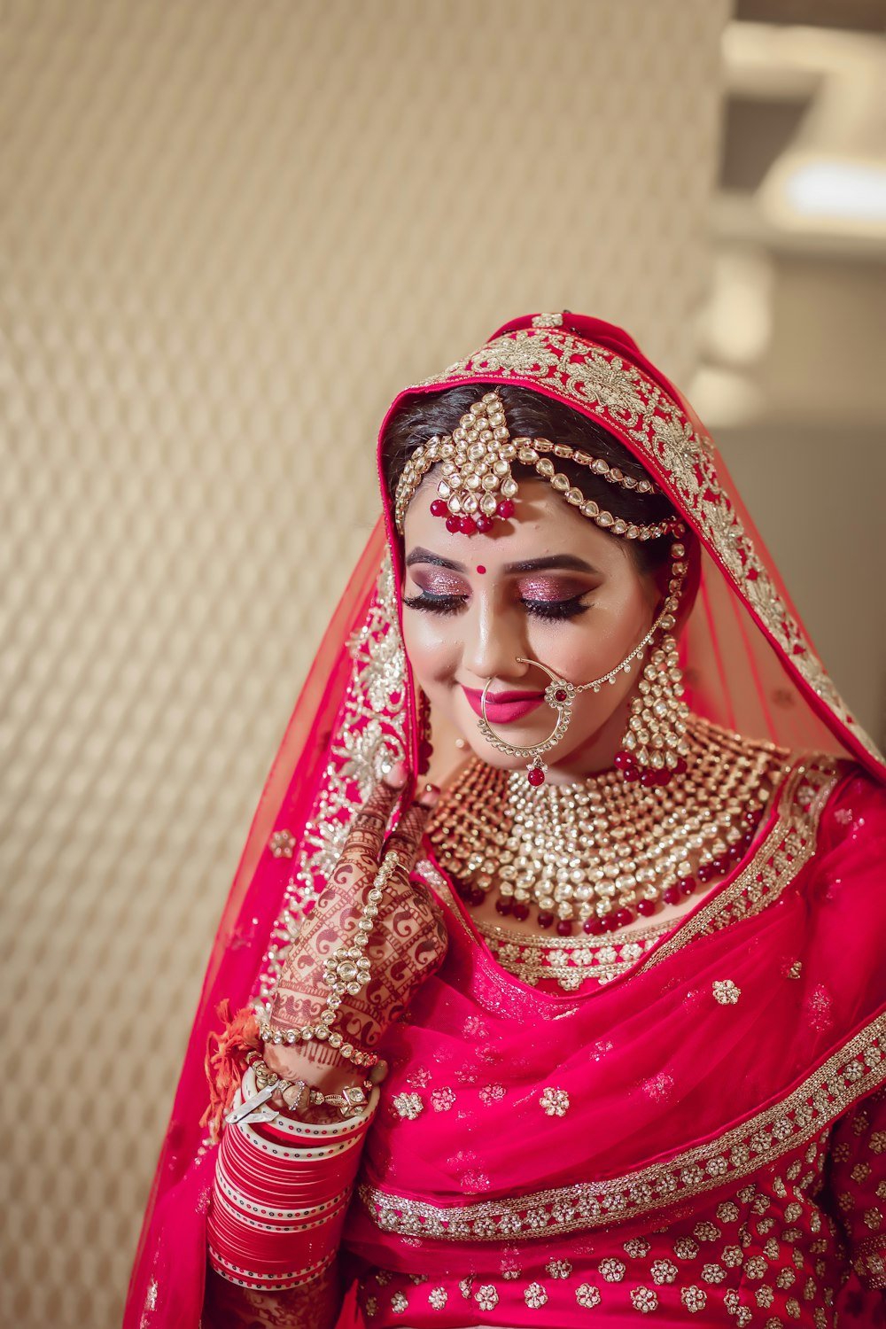 A bride in a red lehenga with gold jewellery and henna