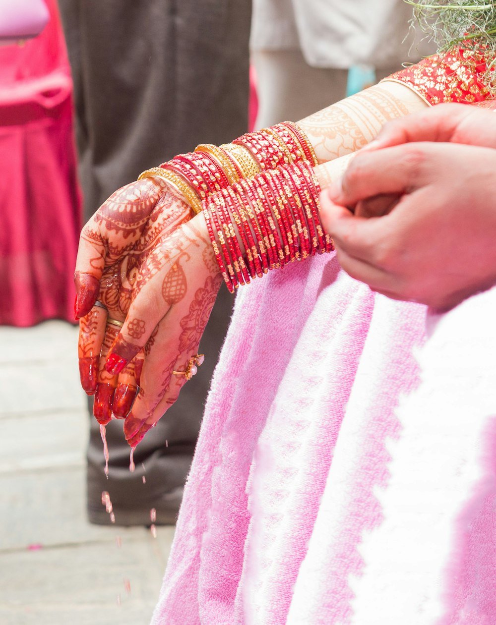 A bride's hands adorned with henna and red bangles