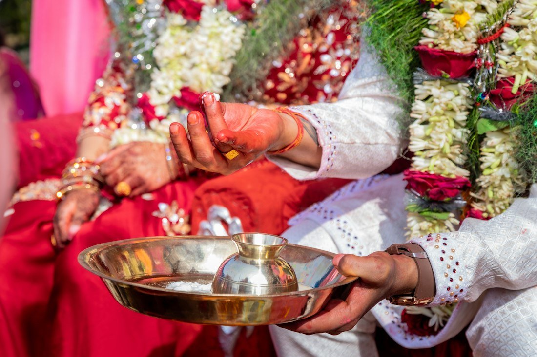 A couple performing a traditional wedding ritual with a brass plate